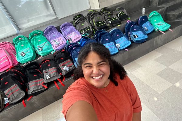 UCLI Associate Director, Sabrina Ruiz-Monroy with backpacks sorted by color and staged on the steps at Meadowlark Elementary before doors opened.