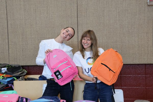 UCLI  2026 Summer Ambassador Ryan Calvert and Executive Director Kaitlyn Pieper sorting through backpacks before families arrived at Backman Elementary.